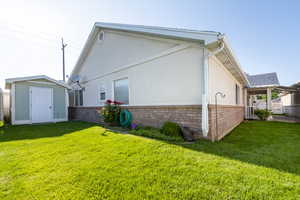 Back of property featuring brick siding, a lawn, and stucco siding