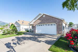 Single story home with brick siding, driveway, a gate, and a garage