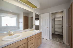 Bathroom featuring tile patterned floors, double vanity, a garden tub, and a walk in closet