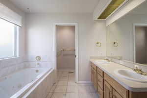 Full bath with double vanity, a whirlpool tub, tile patterned floors, and baseboards