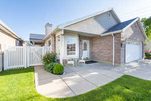 View of front of property with a garage, brick siding, a chimney, and concrete driveway