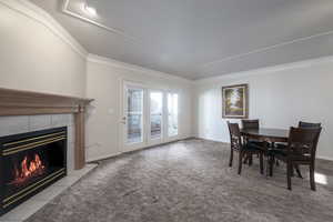 Carpeted dining space with a fireplace, crown molding, and baseboards