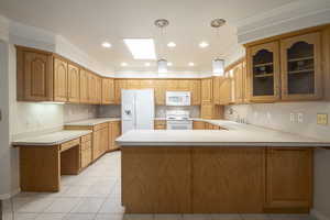 Kitchen with white appliances, a sink, glass insert cabinets, a peninsula, and light countertops