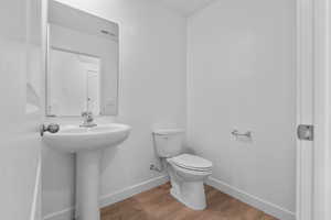Bathroom featuring wood finished floors, toilet, and baseboards