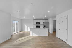 Kitchen with appliances with stainless steel finishes, baseboards, recessed lighting, white cabinetry, and light wood finished floors