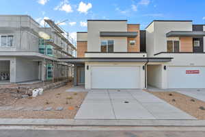 View of front of house featuring stucco siding, a garage, and concrete driveway