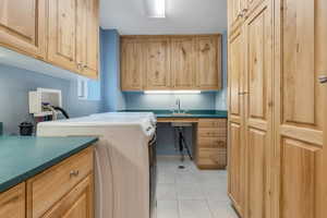 Washroom featuring cabinet space, washer and dryer, and light tile patterned flooring