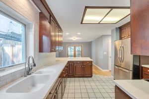 Kitchen with freestanding refrigerator, a sink, light countertops, light tile patterned floors, and a peninsula