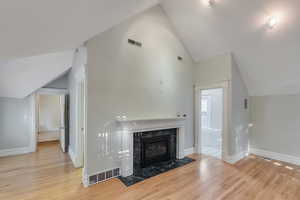 Unfurnished living room with wood finished floors, baseboards, and high vaulted ceiling