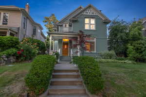 Victorian-style house with a balcony, a chimney, and a front yard