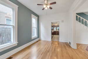 Spare room with stairway, ceiling fan, light wood-style flooring, and baseboards