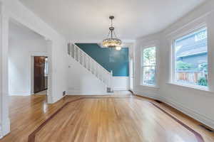 Empty room featuring light wood finished floors, stairs, and baseboards