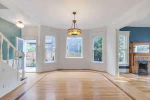 Unfurnished living room with wood finished floors, stairs, plenty of natural light, and a fireplace with flush hearth