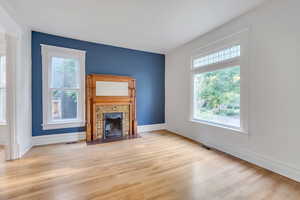Unfurnished living room with light wood-style floors, a fireplace, and baseboards