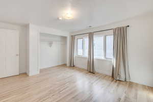 Unfurnished bedroom featuring wood finished floors, a closet, and baseboards