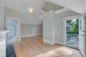 Additional living space with vaulted ceiling, light wood-style floors, and baseboards