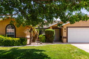 View of front of home featuring stucco siding, a front yard, and a garage