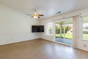 Unfurnished living room with light wood-style flooring, ceiling fan, baseboards, plenty of natural light, and vaulted ceiling
