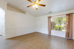 Empty room with vaulted ceiling, crown molding, light wood-style flooring, a ceiling fan, and baseboards