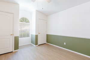 Unfurnished room featuring wood finished floors, lofted ceiling, a ceiling fan, and baseboards