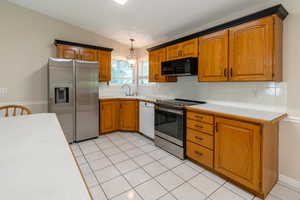 Kitchen with stainless steel appliances, light countertops, decorative backsplash, and brown cabinets