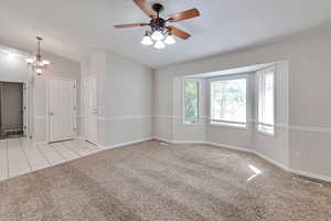 Carpeted spare room with ceiling fan, lofted ceiling, and tile patterned flooring