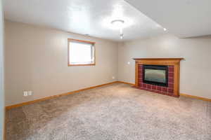 Unfurnished living room with carpet, a tile fireplace, and a textured ceiling