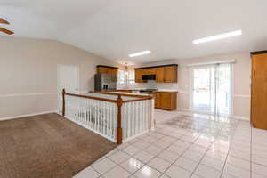 Kitchen featuring stainless steel fridge, black microwave, electric range oven, light tile patterned floors, and healthy amount of natural light