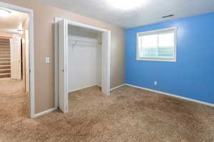 Unfurnished bedroom featuring carpet flooring, a closet, and a textured ceiling