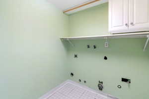 Washroom featuring gas dryer hookup, cabinet space, washer hookup, light tile patterned floors, and electric dryer hookup