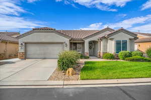 View of front of property featuring stucco siding, an attached garage, driveway, and stone siding