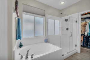 Bathroom featuring a shower stall, a spacious closet, and a garden tub