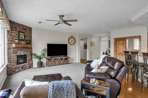 Living room featuring a ceiling fan, a fireplace, and baseboards