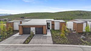 View of front of property featuring a standing seam roof, metal roof, a mountain view, concrete driveway, and a garage