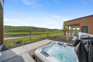 View of swimming pool with a water and mountain view, a hot tub, and a patio
