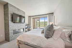 Bedroom with access to outside, a stone fireplace, and carpet