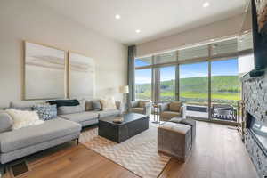 Living area with a stone fireplace, hardwood / wood-style floors, and recessed lighting
