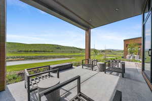 View of patio / terrace with a water and mountain view and view of golf course