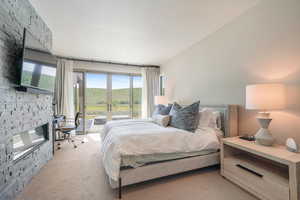 Carpeted bedroom with access to outside and a fireplace