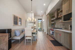 Kitchen with a sink, premium stove, wall chimney exhaust hood, light countertops, and open shelves
