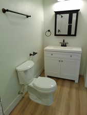 Bathroom featuring wood finished floors, toilet, vanity, and baseboards