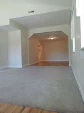 Formal living room leading into a den/office space, featuring arched walkways