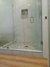 Bathroom in bedroom with a marble finish shower and tile floor.