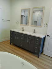Master bathroom with double vanity, wood finished floors, baseboards, and a shower
