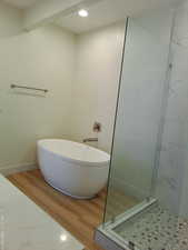 Master bathroom with tiled shower, wood finished floors, a freestanding bath, recessed lighting, and baseboards.