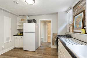 Kitchen with stainless steel appliances, tile countertops, light wood-style flooring, open shelves, and a textured ceiling