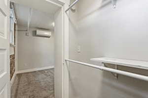Spacious closet featuring a wall unit AC and carpet