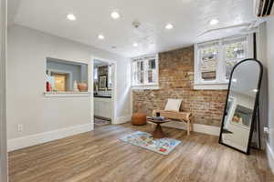 Living area with baseboards, light wood finished floors, recessed lighting, an AC wall unit, and brick wall