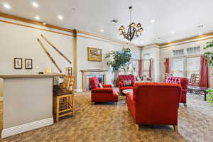 Carpeted living area with ornamental molding, a chandelier, recessed lighting, baseboards, and a fireplace