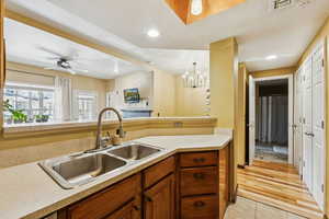 Kitchen featuring a sink, light countertops, light tile patterned floors, brown cabinets, and ceiling fan